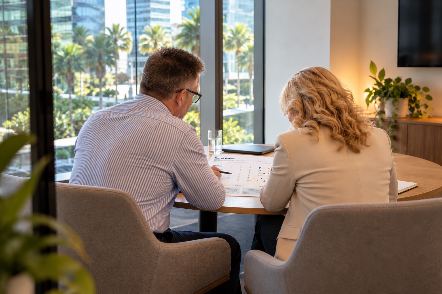 A coach and a leader working through a feedback report together at a small table